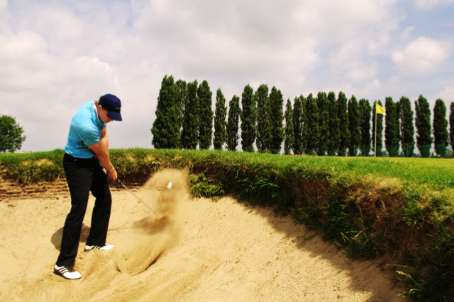 Golfer hitting ball from sand trap