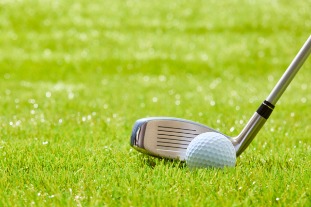 Golf club and ball on green grass
