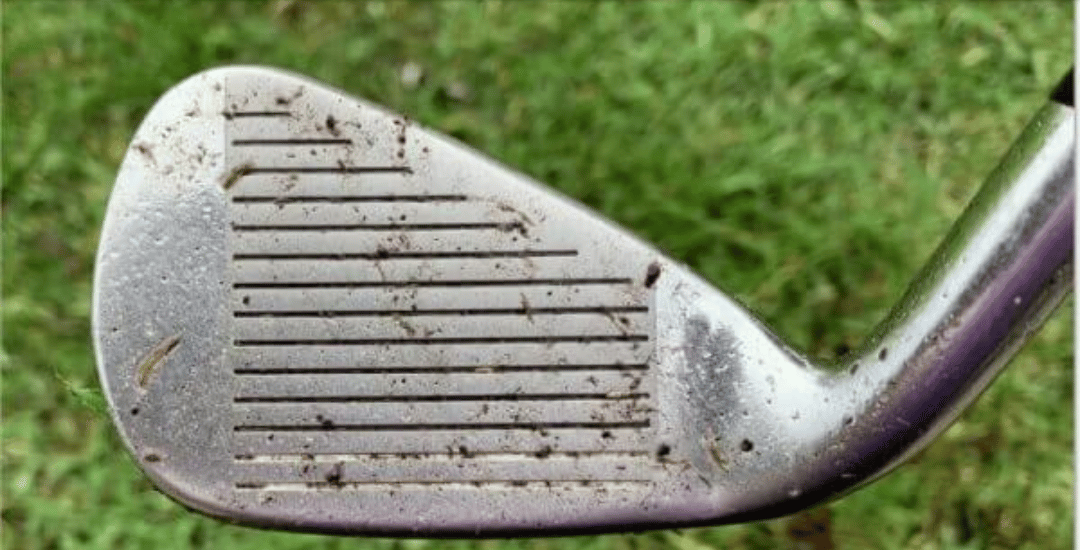 Golf club face with mud and grass debris