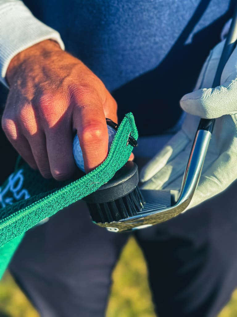 Preparing golf club with cleaning brush