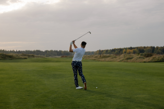 Golfer swinging club on lush green course