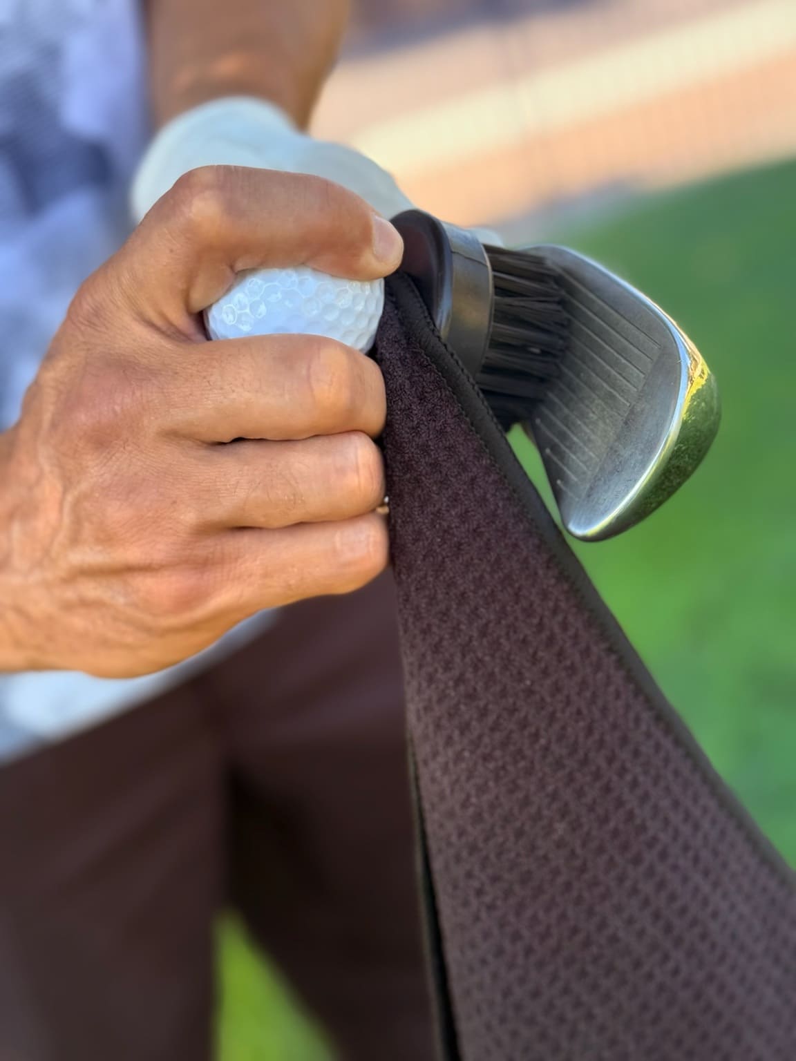 Cleaning golf club with towel and golf ball