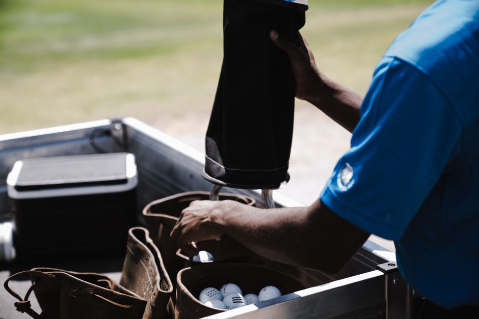 Person handling golf balls and bags outdoors