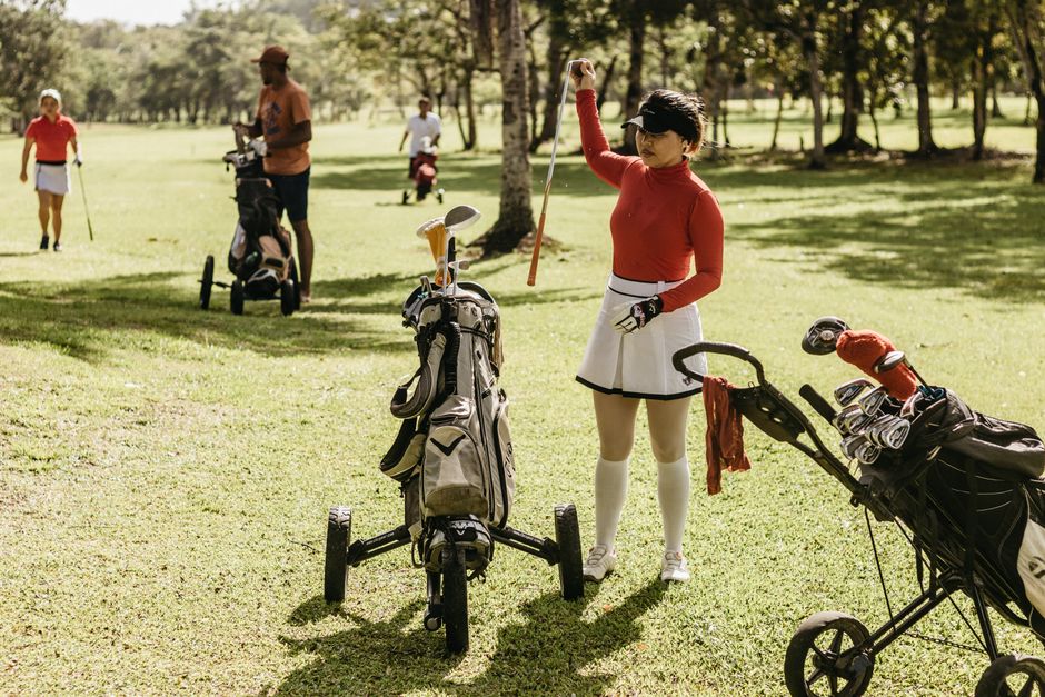 Woman in red top with golf clubs outdoors