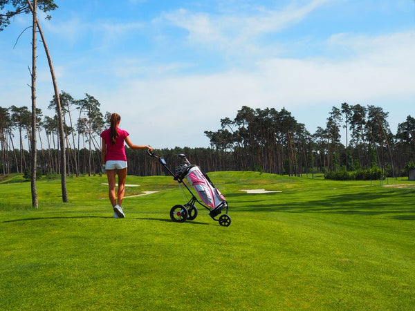 Woman with golf trolley on green course