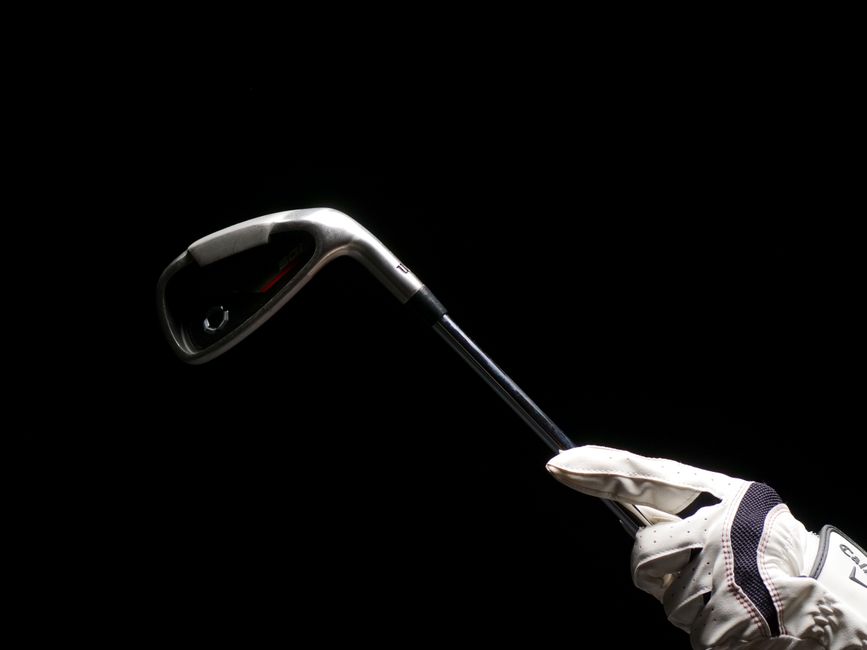 Gloved hand holding a golf iron club