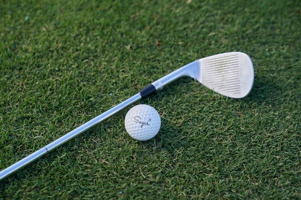Golf club and ball on green grass