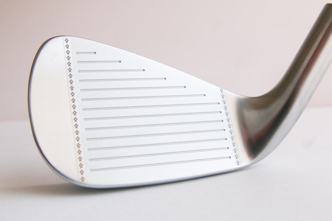 Close-up of a polished golf iron clubface with grooves