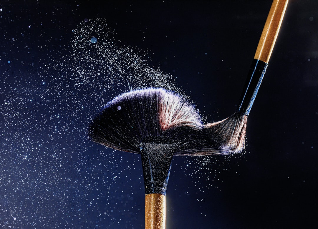 Two brushes spraying fine particles against a dark starry background