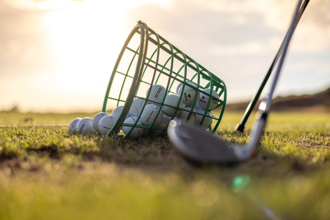Basket of golf balls with golf club on grass