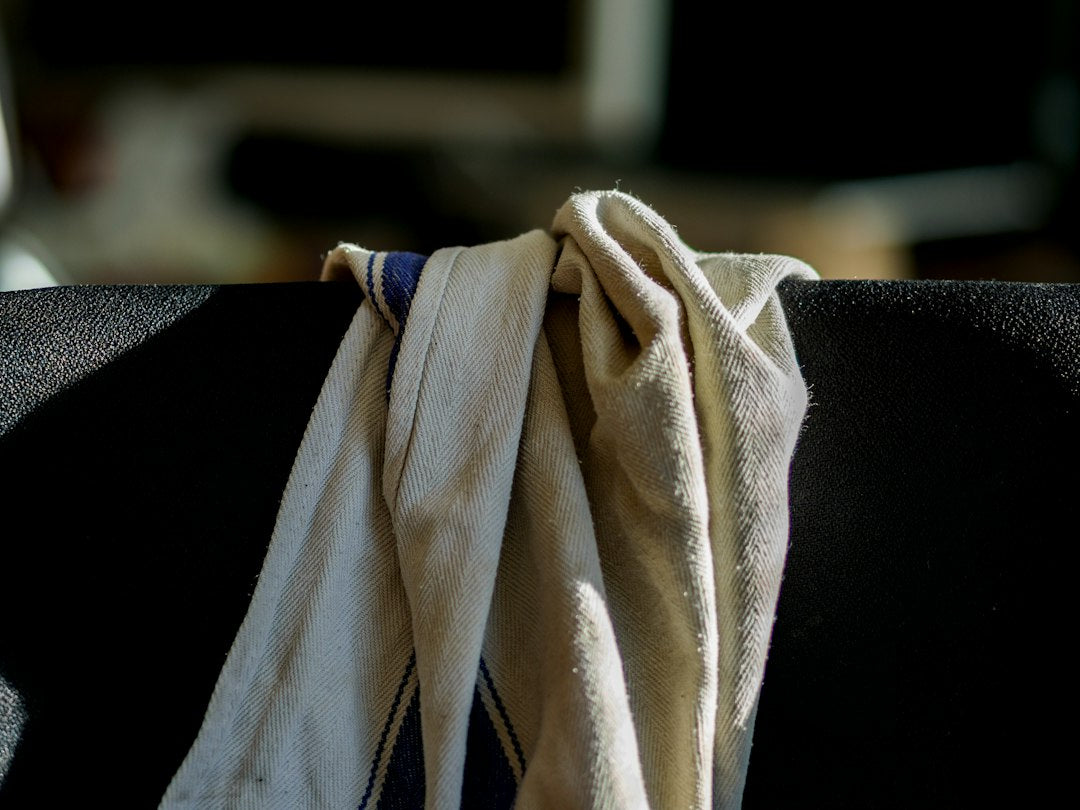 White towel with blue stripe on black chair
