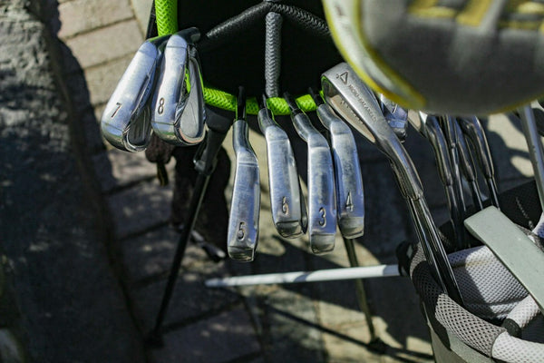 Several numbered golf clubs in a golf bag