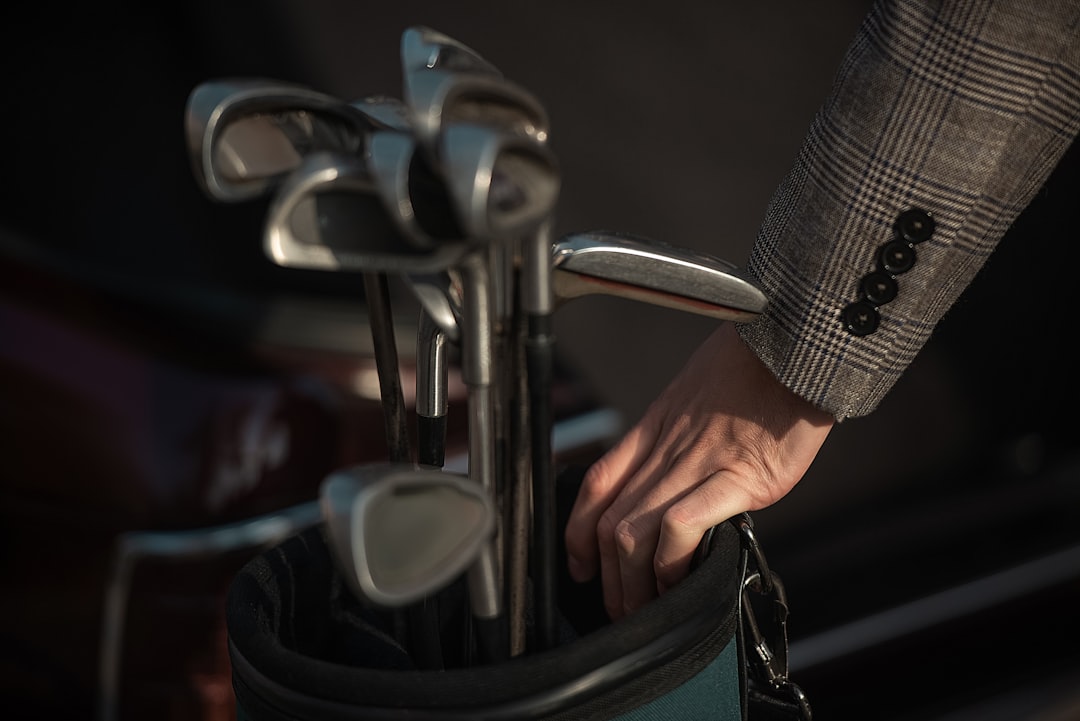 Person in suit grabbing golf club from bag