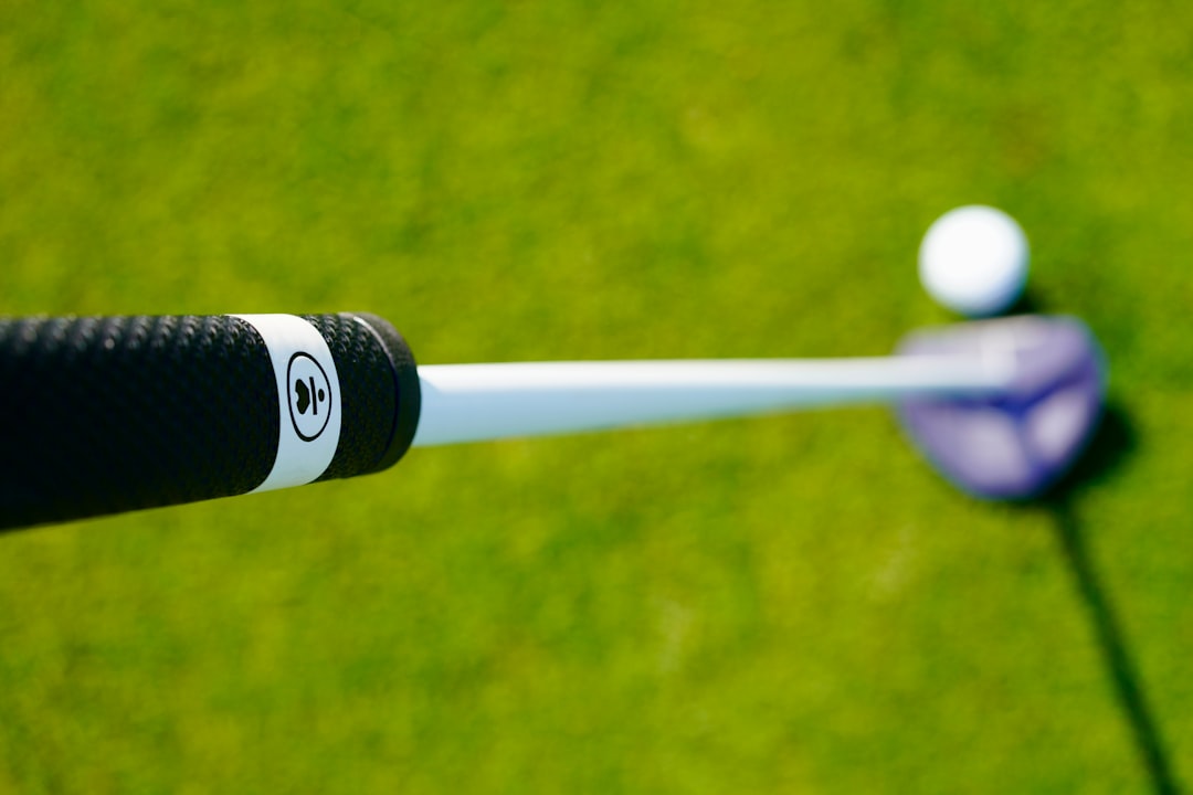 Golf club aimed at ball on grass