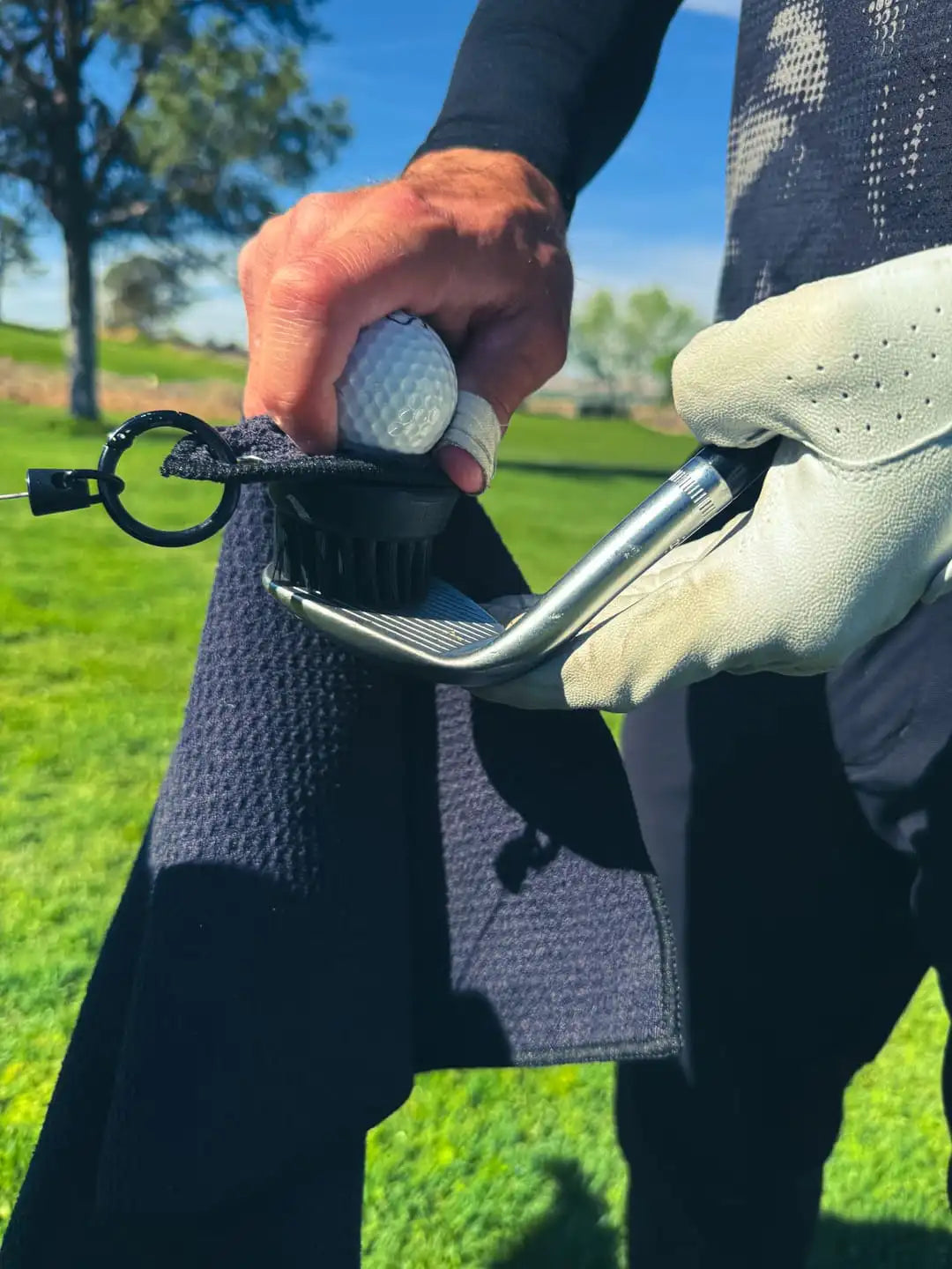 Black Duo Pro brush cleaning a golf club face mid-round