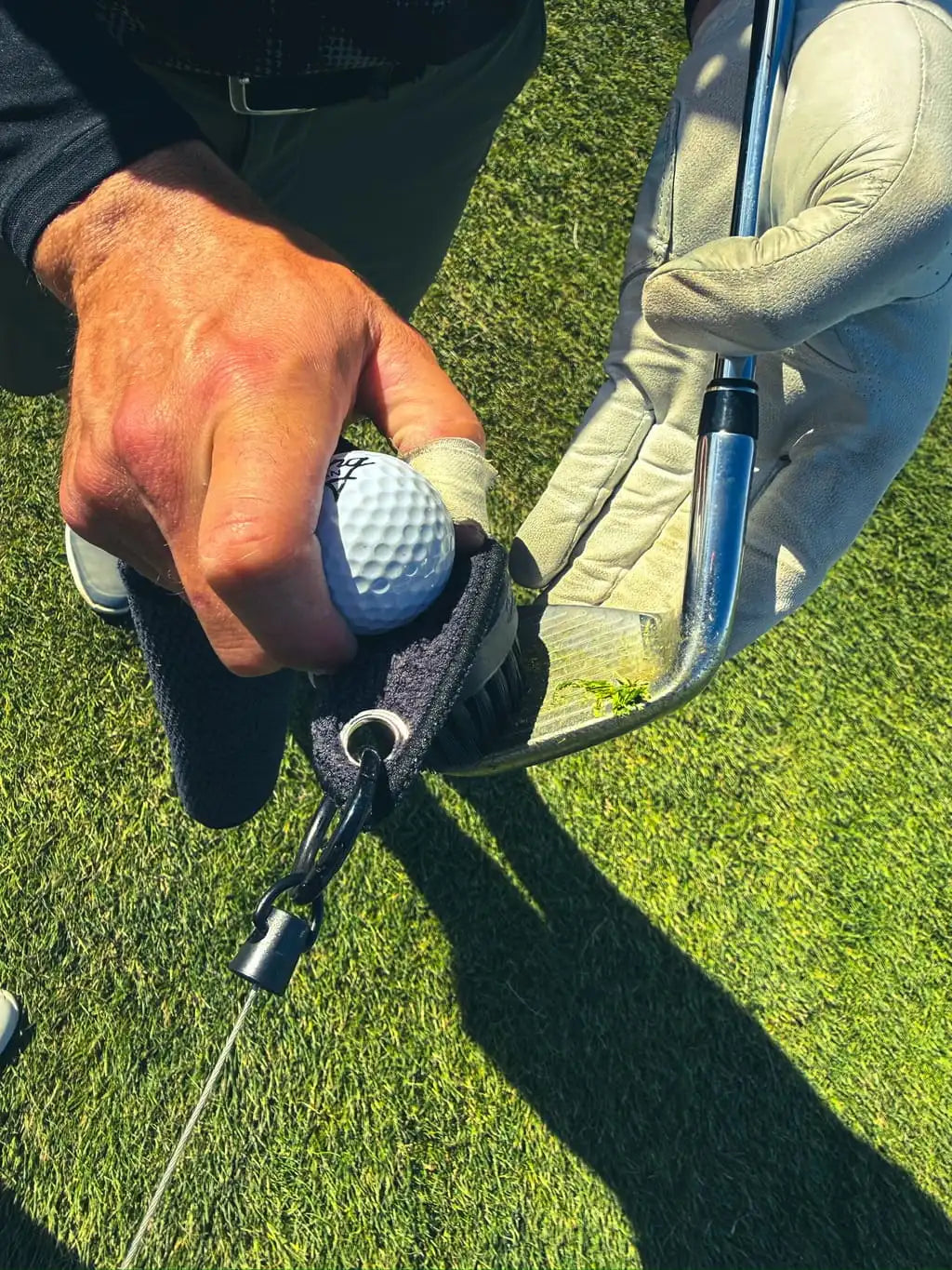 Black Duo Pro brush cleaning grass and dirt from golf club grooves