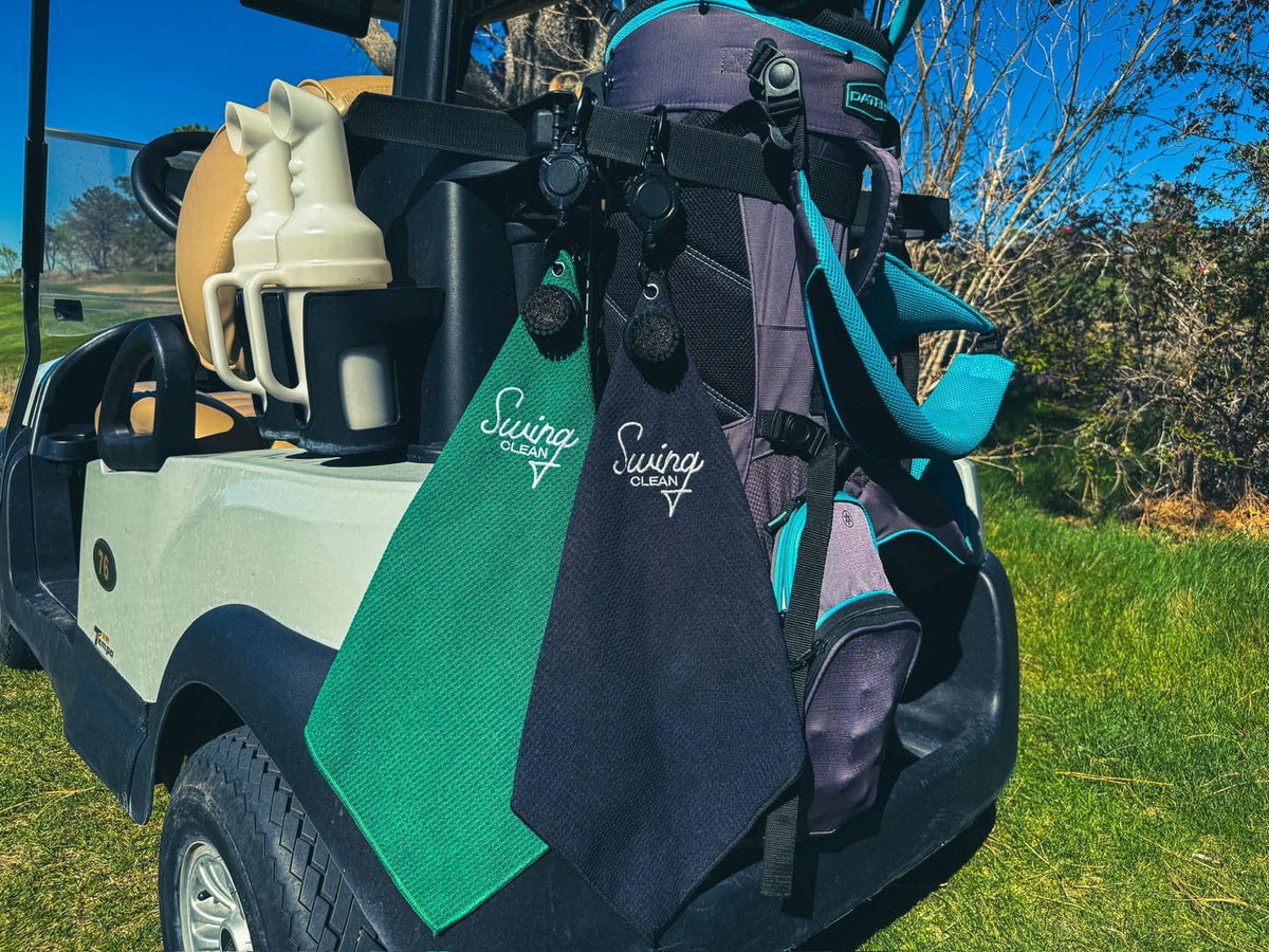 Black and green Duo Pro towels hanging from golf bags on a golf cart