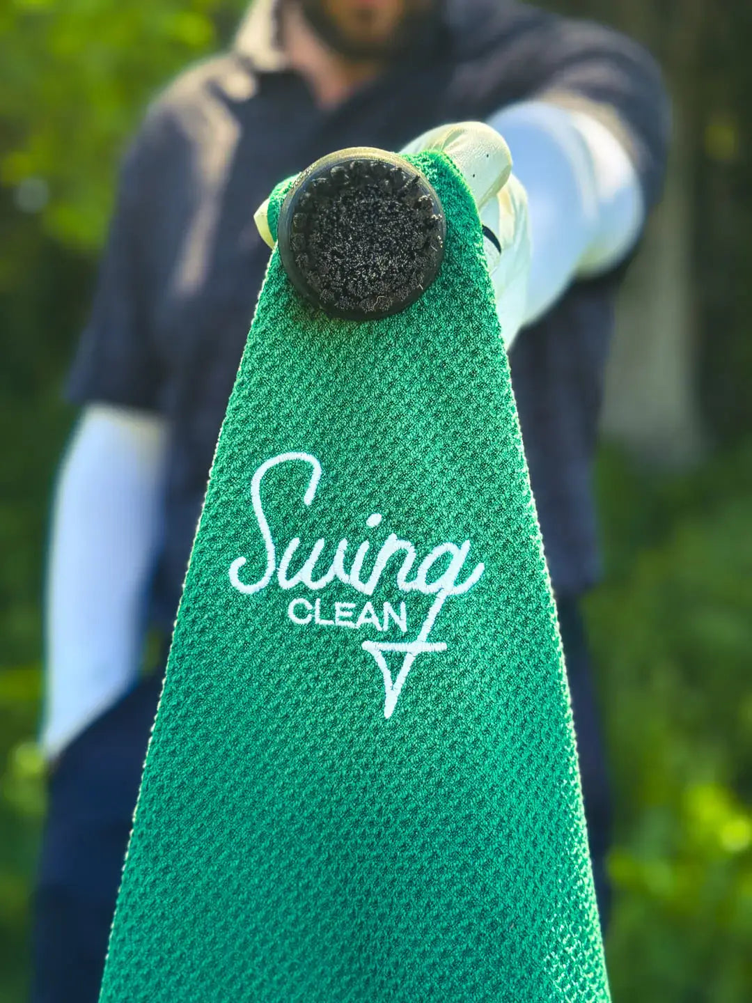 Golfer holding the Bentgrass Green Duo Pro waffle towel and brush combo