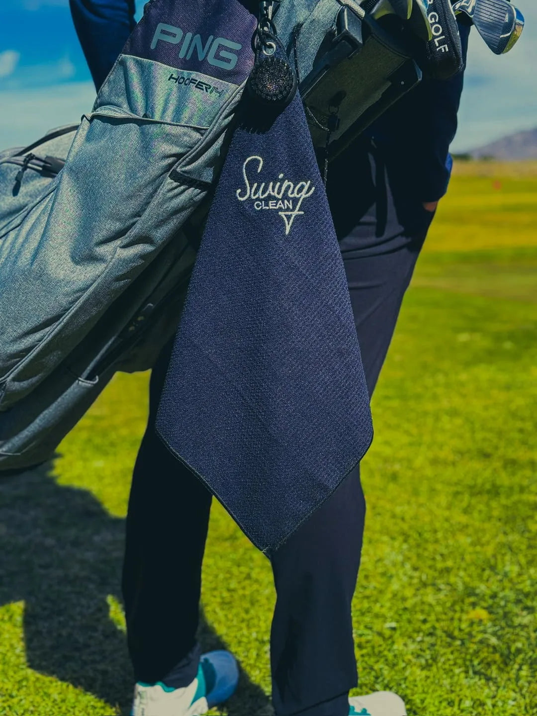 Black Swing Clean Duo Pro towel hanging from a golf stand bag on the course