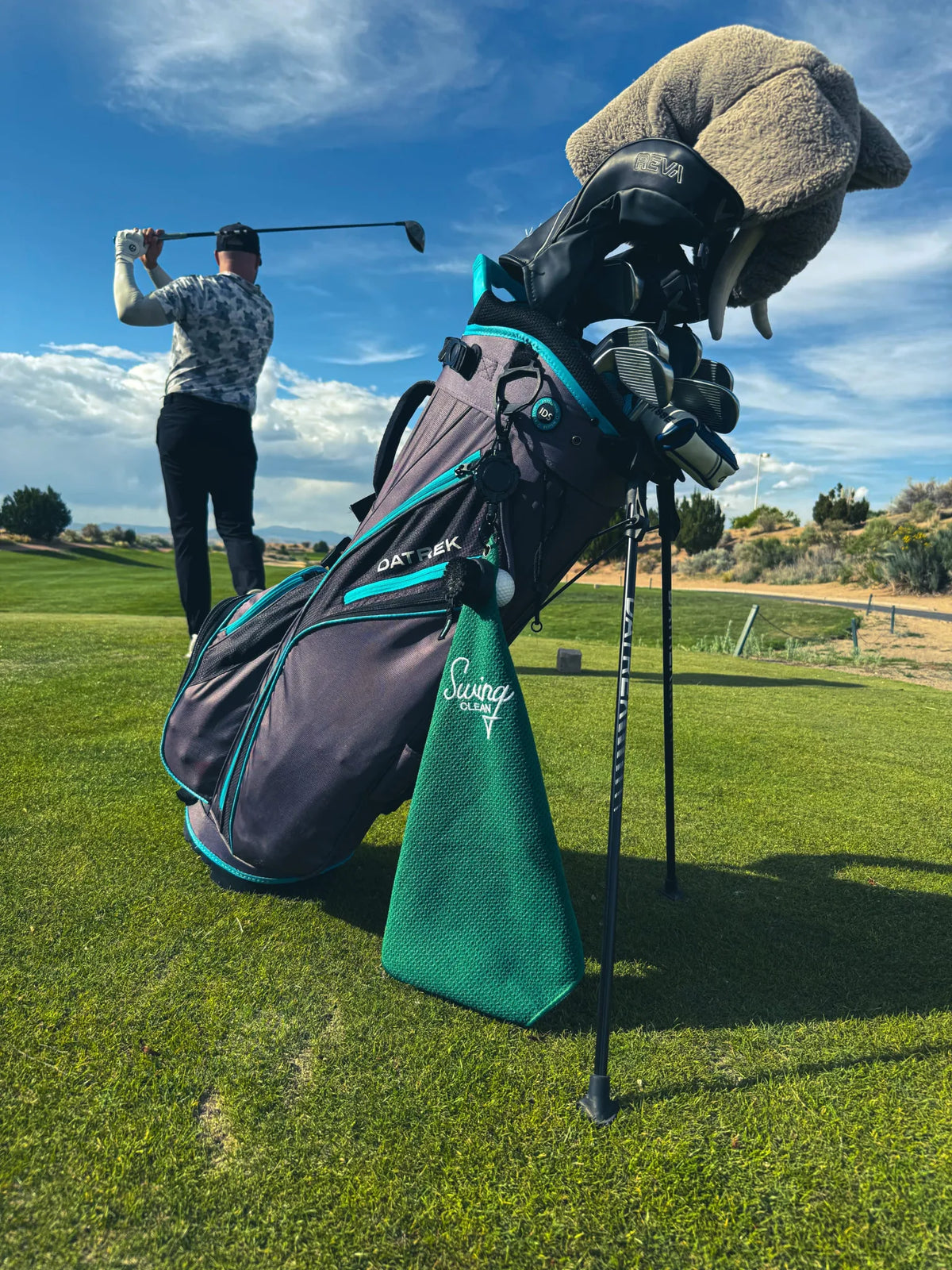 Golfer finishing his swing with the green Swing Clean Duo Pro towel hanging from his bag